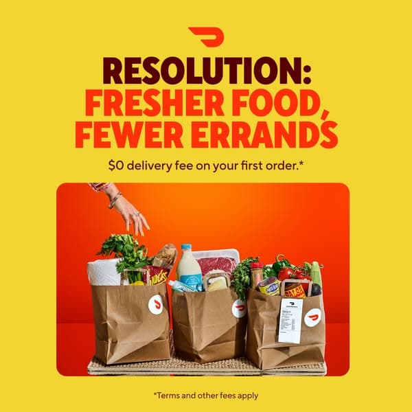 A DoorDash ad with a bright yellow background featuring three paper grocery bags filled with fresh food against an orange backdrop; the text reads, "RESOLUTION: FRESHER FOOD, FEWER ERRANDS" and "$0 delivery fee on your first order.*" with a small note "*Terms and other fees apply.