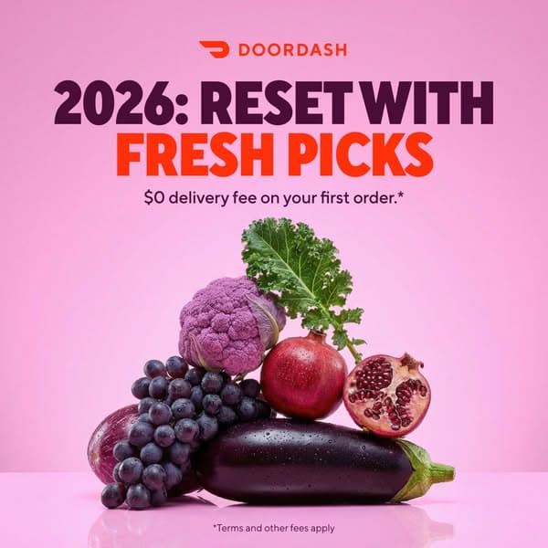 DoorDash ad banner with a pink background featuring a stack of fresh fruits and vegetables including grapes, purple cauliflower, pomegranate, kale, and eggplant, reading "2026: RESET WITH FRESH PICKS $0 delivery fee on your first order.*" with "DOORDASH" logo on top and small text "*Terms and other fees apply" at the…