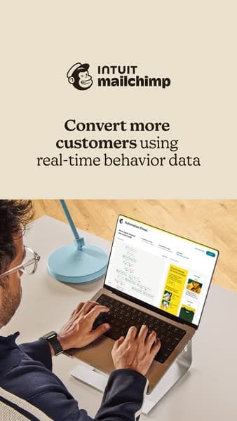 Advertising banner with cream background and a man working on a laptop at a desk, featuring the text "INTUIT mailchimp" and "Convert more customers using real-time behavior data.