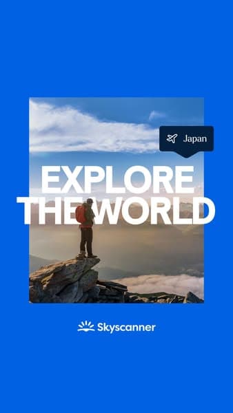 A man with a backpack stands on a rocky cliff overlooking a scenic sky and mountains, with bold white text reading "EXPLORE THE WORLD" and a small label indicating "Japan," plus the Skyscanner logo below, all set against a bright blue background.